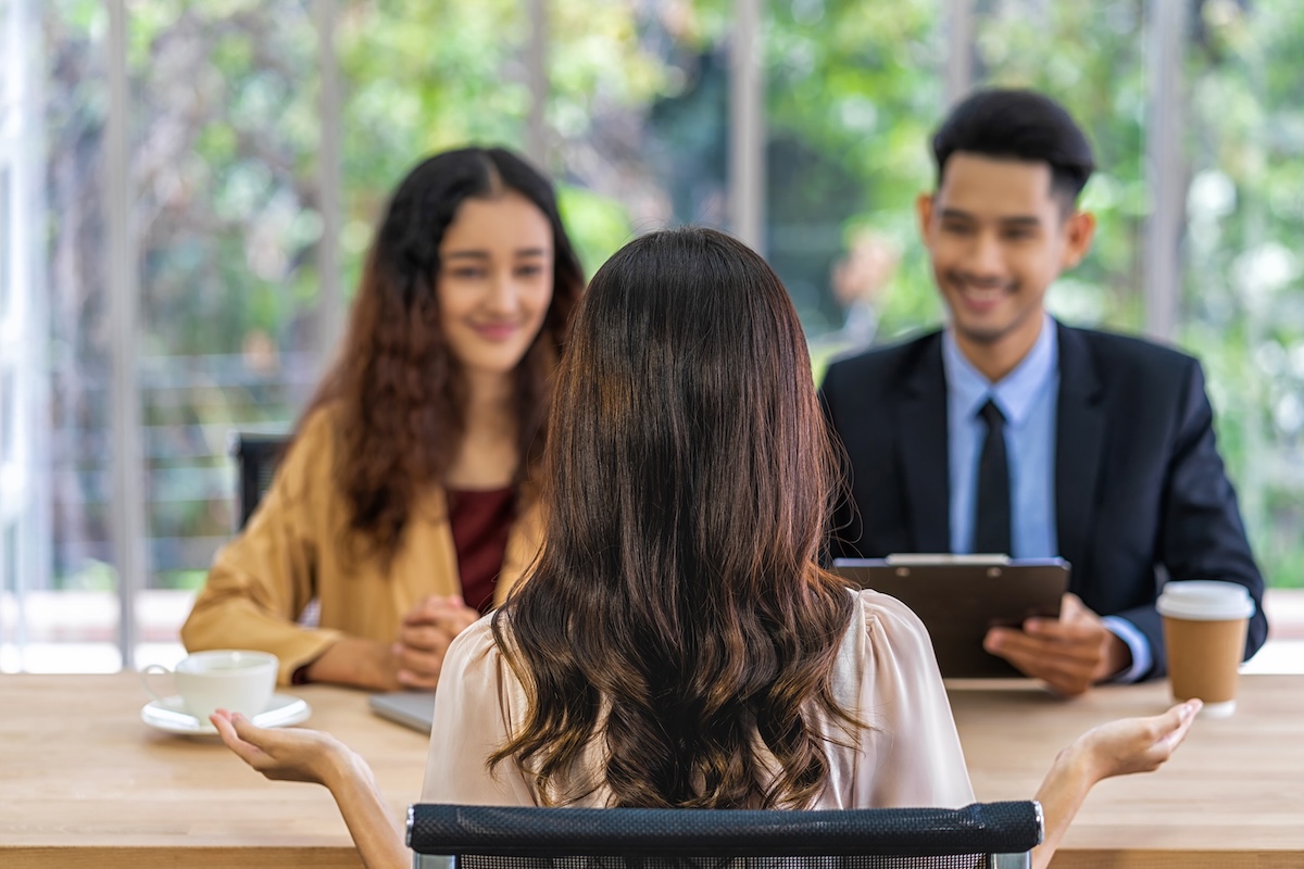 Mujer siendo entrevistada para un trabajo por un hombre y otra mujer. Los entrevistadores parecen estar disfrutando la entrevista.